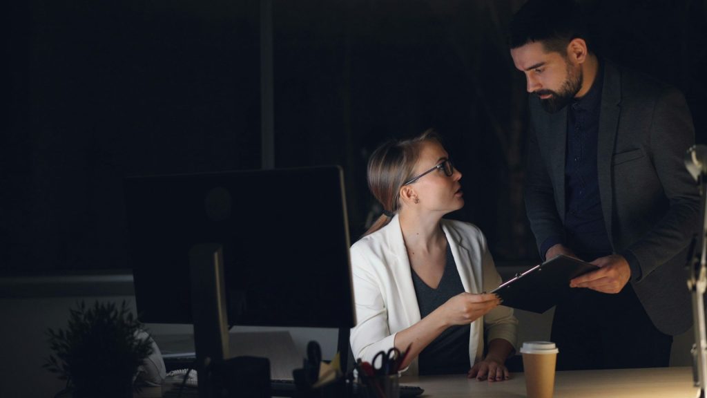 Two colleagues working late in a dimly lit office.